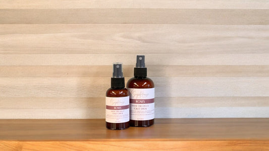 2 Amber colored spritz bottles with roses labels, on wood surface