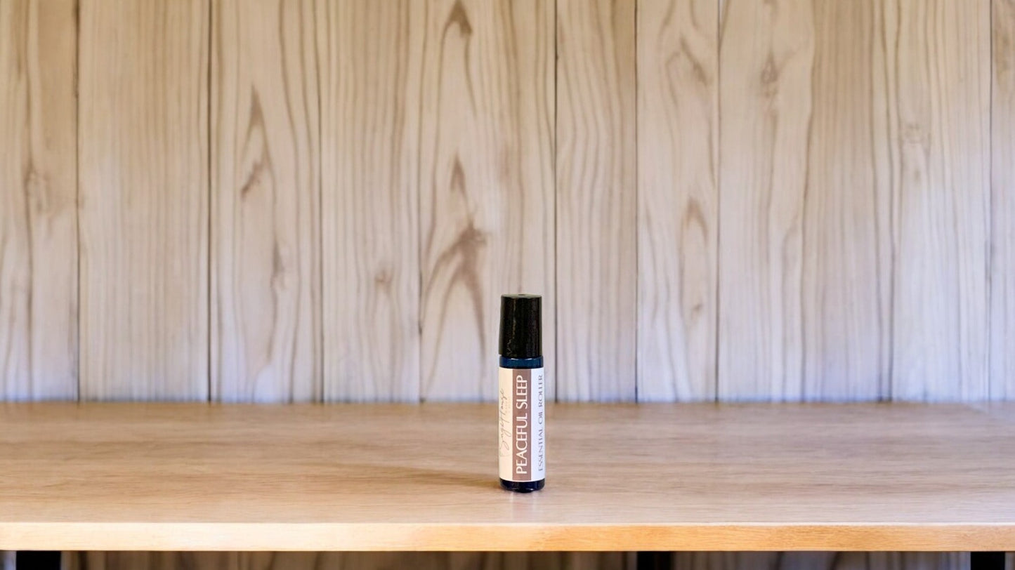 A roller bottle, labeled with 'Peaceful sleep Massage Oil', positioned on a wooden surface.