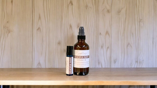 A bottle with a treatment pump, and a roller bottle labeled with 'Peaceful sleep Massage Oil', positioned on a wooden surface.