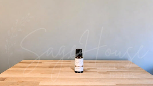 A small bottle of peppermint essential oil is placed on a wooden surface with a plain background.