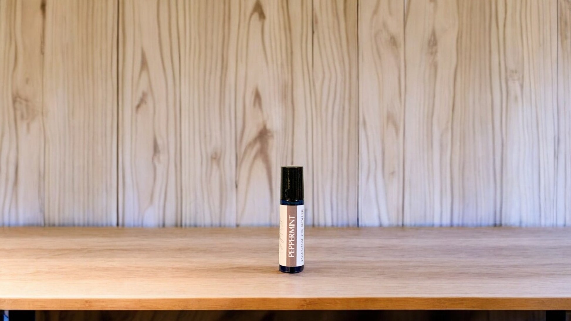 A roller bottle, labeled with 'Peppermint Massage Oil', positioned on a wooden surface.