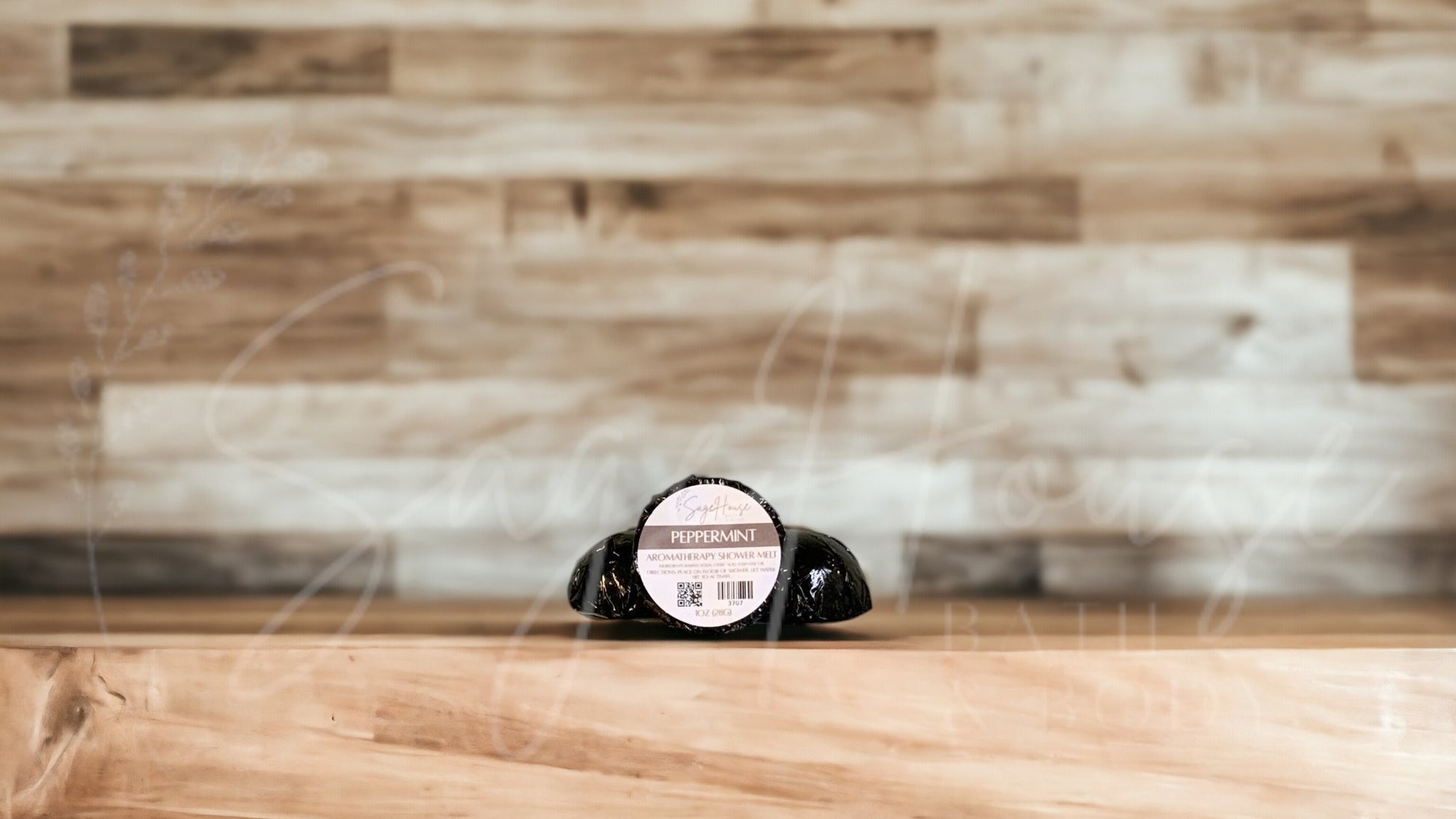 Aromatherapy shower melt in black packaging labeled "peppermint", on wood surface