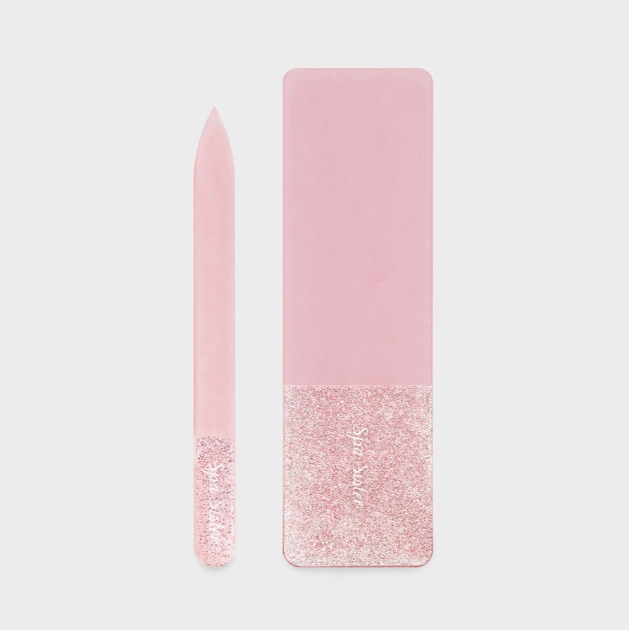 Pink glass nail file with glittery bottom half on a light gray background