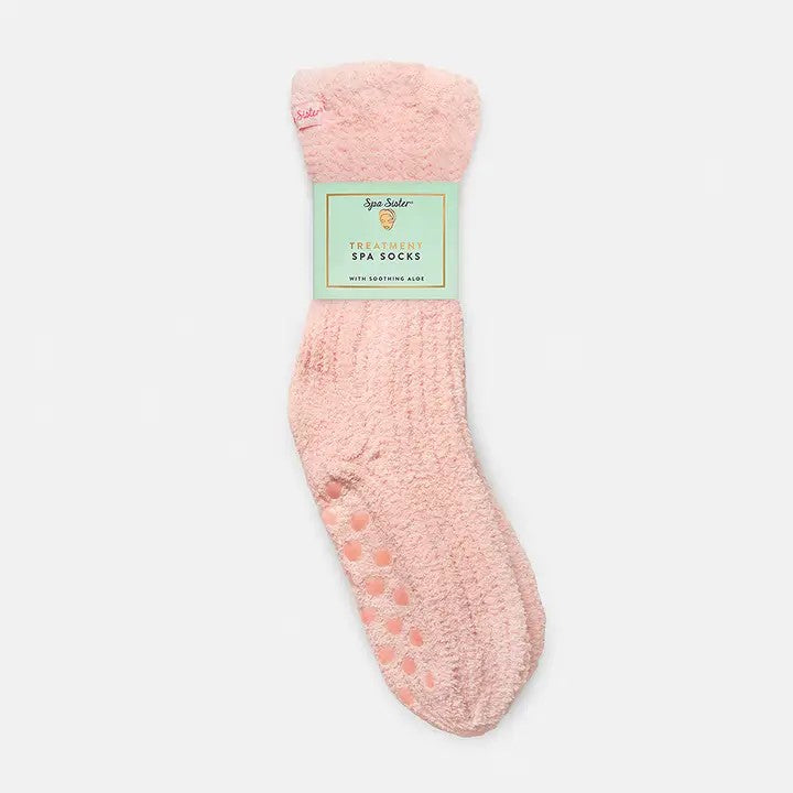 A pair of pink fuzzy spa socks with floor grippers and a label.