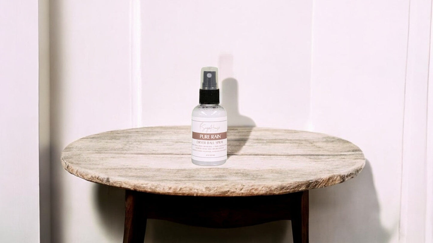 A clear bottle with black spritz top. sitting on a stone table with a white wall in the background