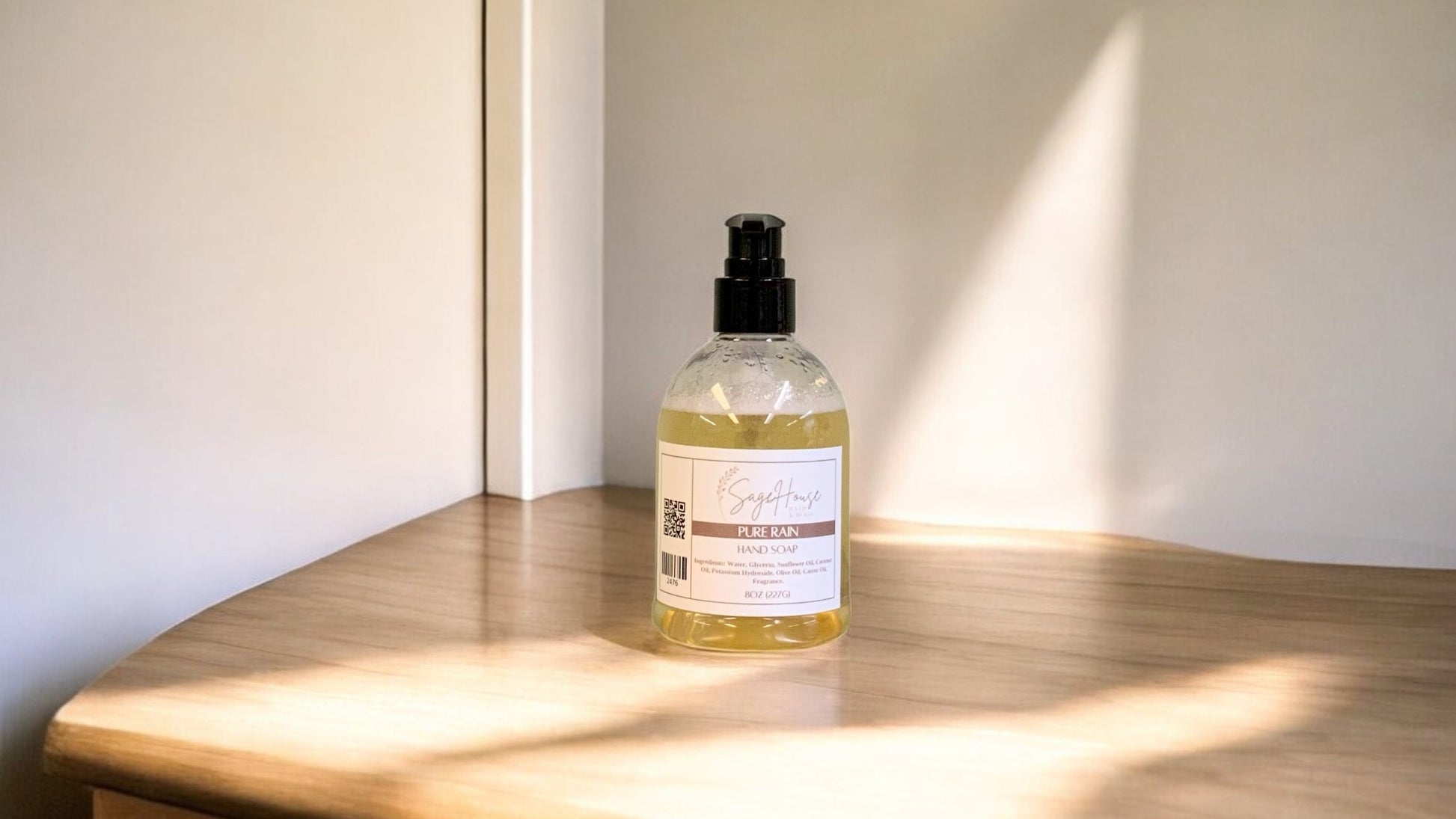 A clear plastic bottle of hand soap with a black cap, placed on a wooden surface with natural lighting.