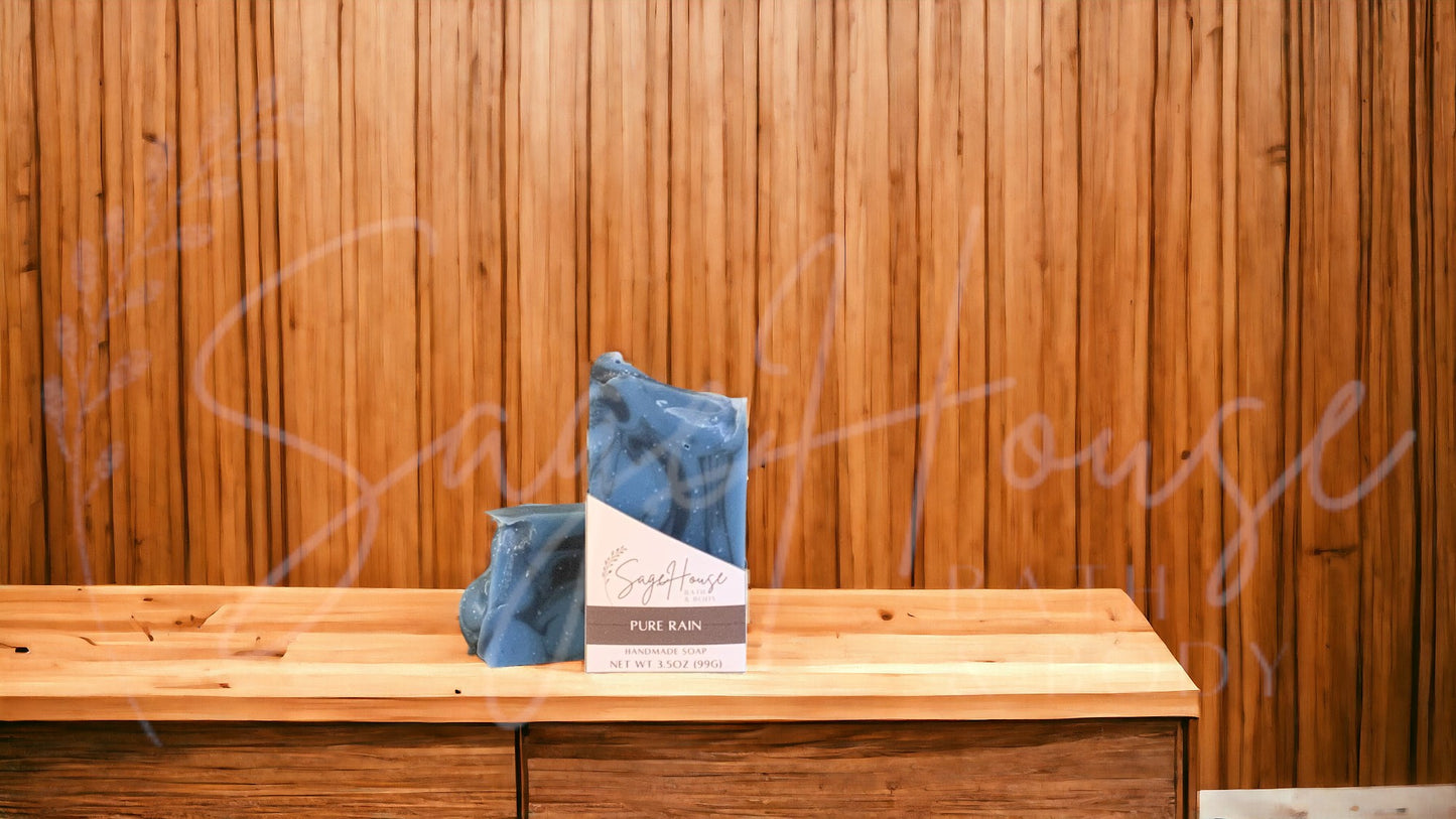 A blue bar of soap with black accents, in a white labeled box, on a wood surface.