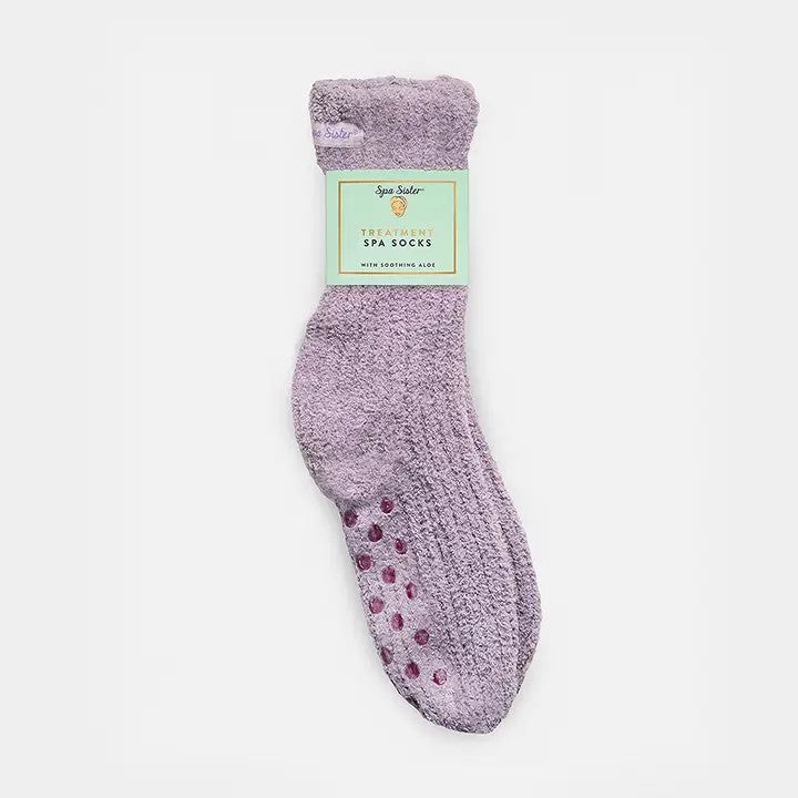 A pair of purple fuzzy spa socks with floor grippers and a label.
