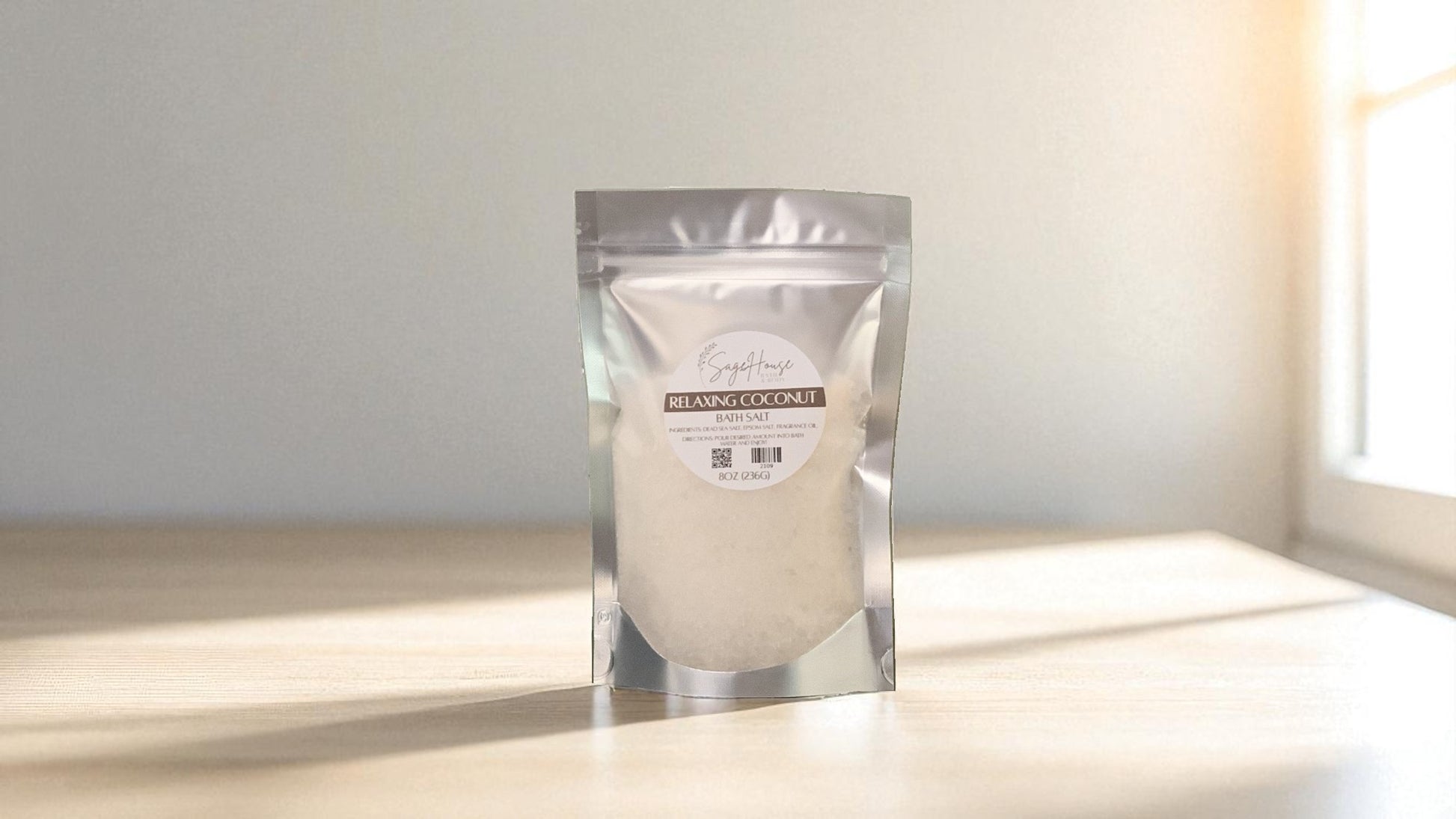 Silver packaging with a clear window of white salt labeled "relaxing coconut" on a wood surface.