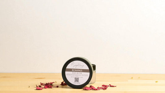 Jar of 'Romance' body butter on a wooden surface with dried flowers