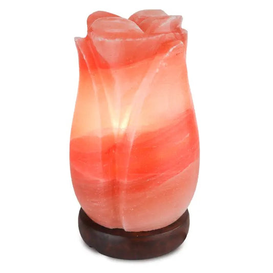 A pink Himalayan salt lamp with an intricate rose design, placed on a dark base.