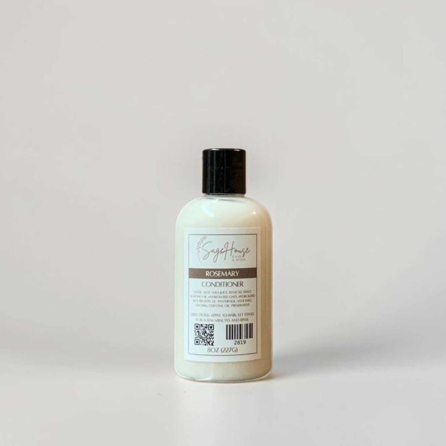 A bottle of conditioner with a black lid and white label. Sitting on a white background.