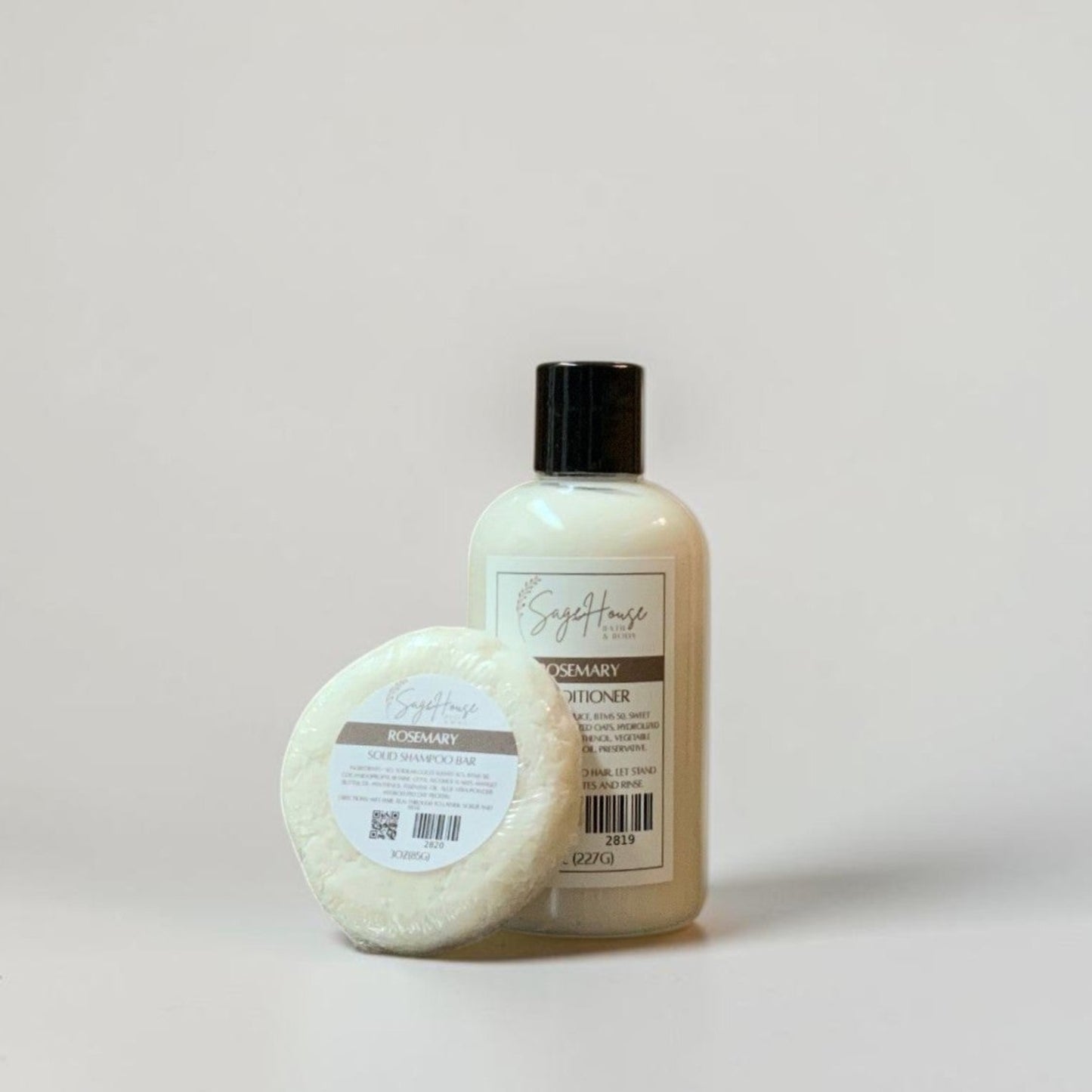 A round shampoo bar and bottle of conditioner on a white background.