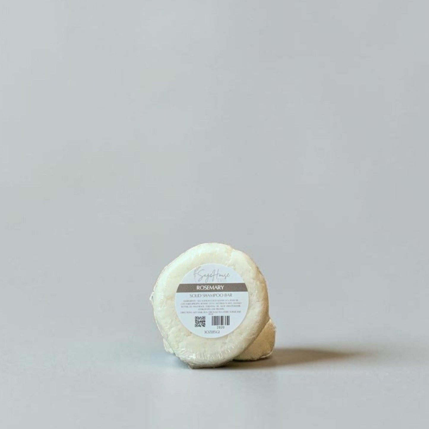 Round shampoo bar with a label on a light gray background