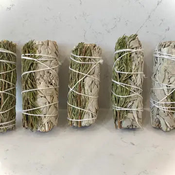 5 bundles of Rosemary and sage, wrapped with string and placed on a white marble surface