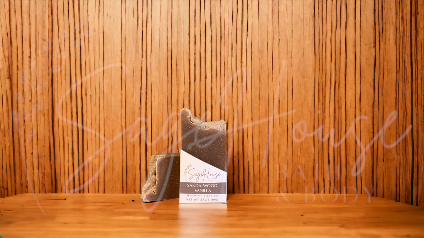 A dark brown bar of soap in a white labeled box, on a wood surface.