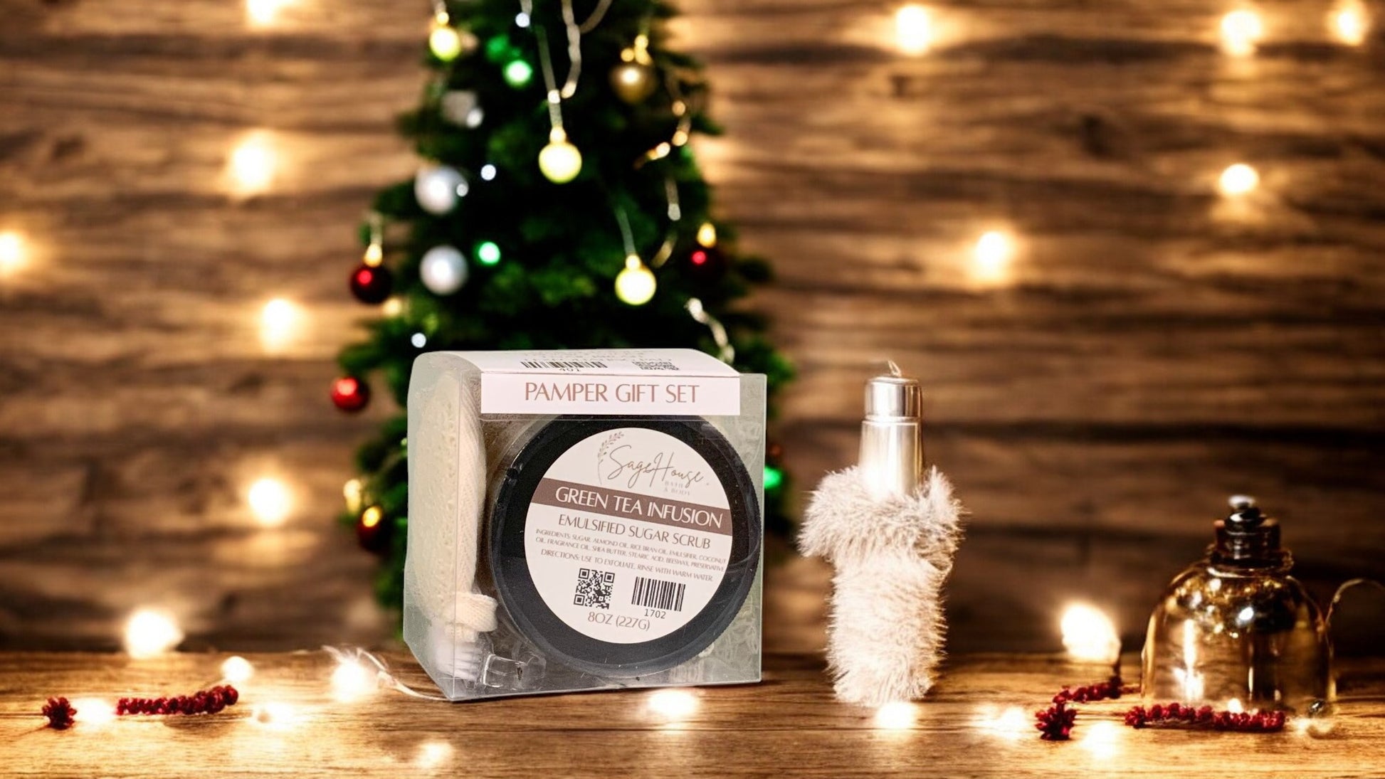 A square clear box containing a jar of body scrub and various other spa products. On a wood surface with christmas theme in background
