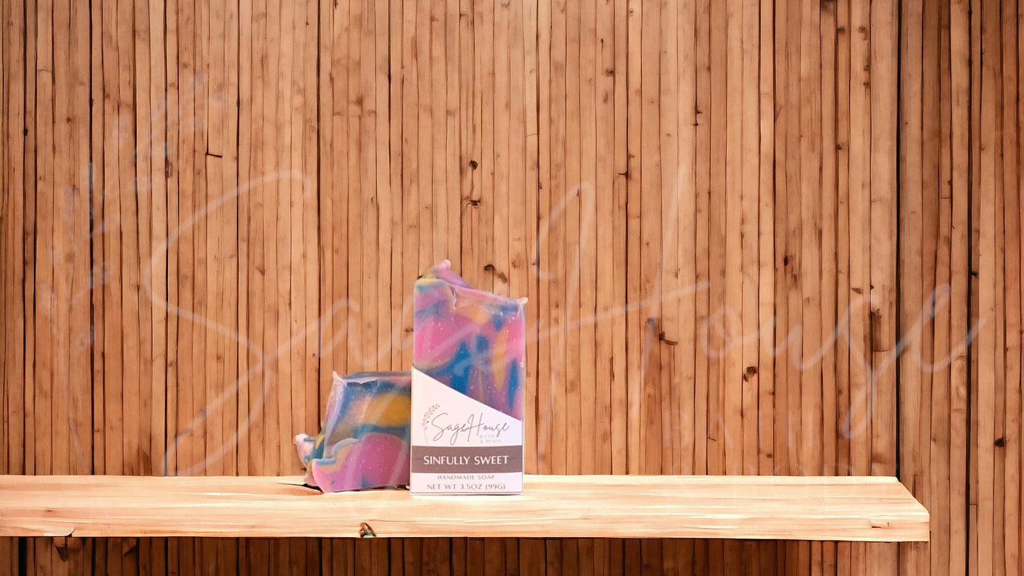A pink bar of soap with blue and gold accents in a white labeled box, on a wood surface.