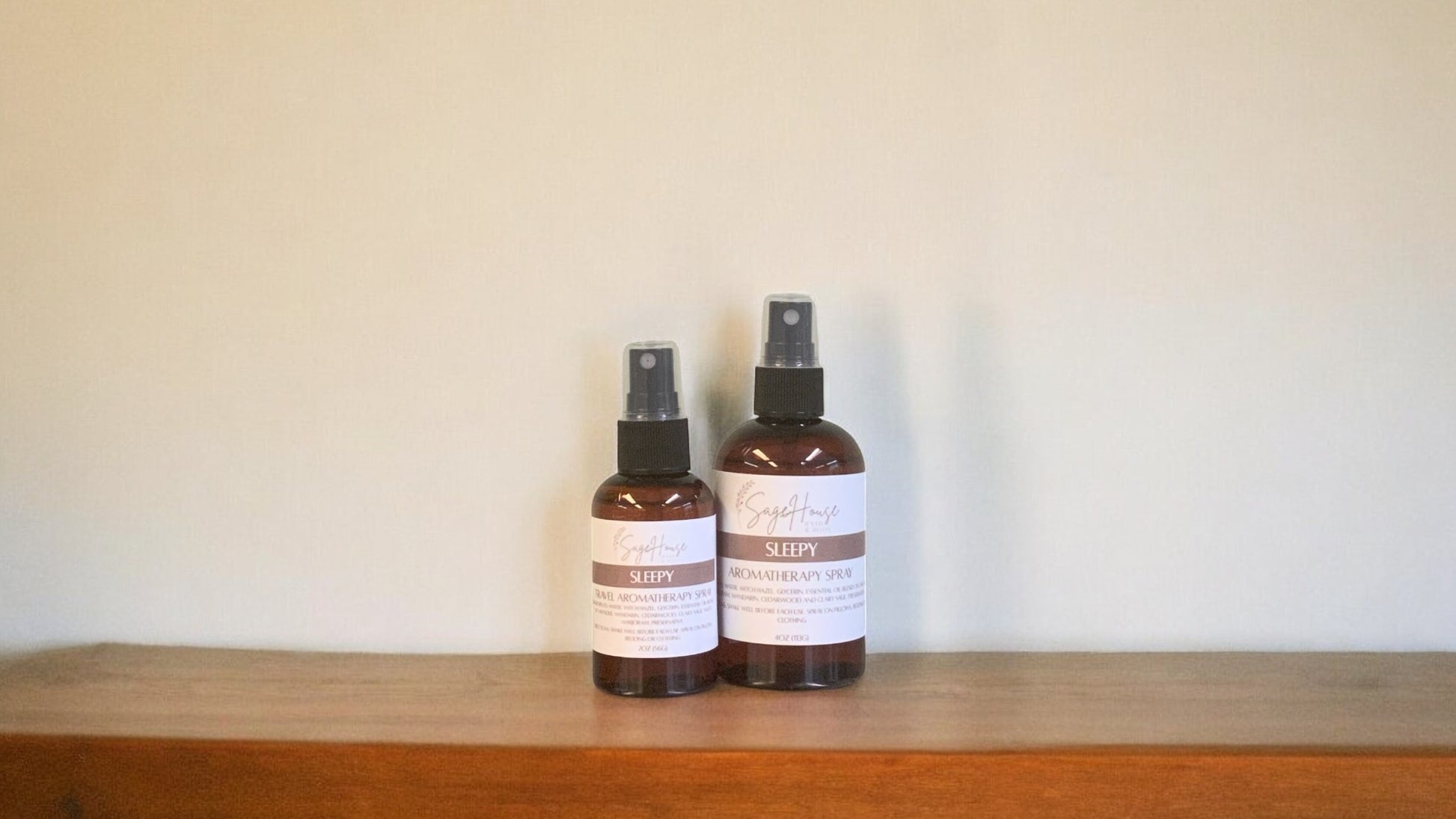 Amber colored spritz bottles in two sizes, both with sleepy label, on wood surface. Sold individually.