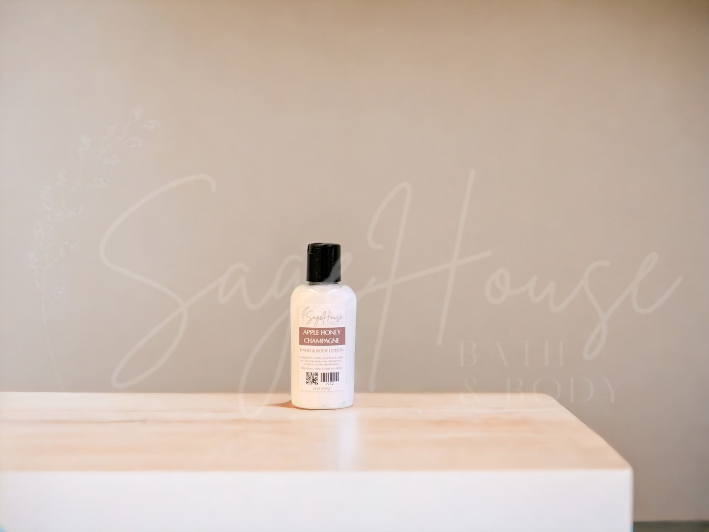 A small bottle of lotion with a black disc cap. Sitting on a white countertop with neutral background