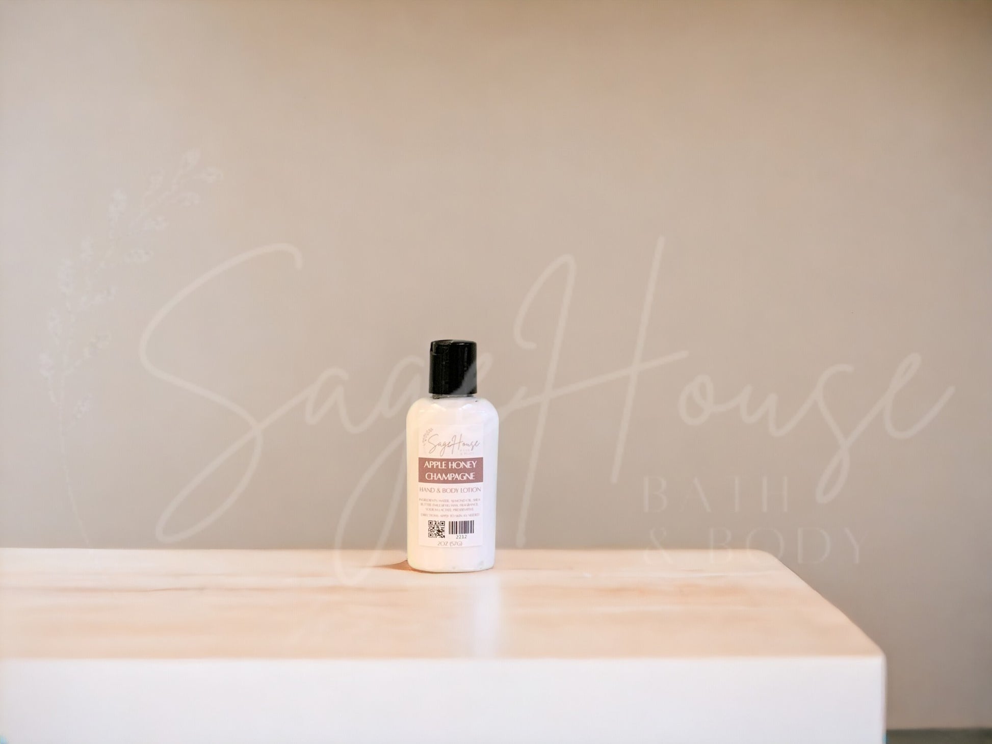 A small bottle of lotion with a black disc cap. Sitting on a white countertop with neutral background
