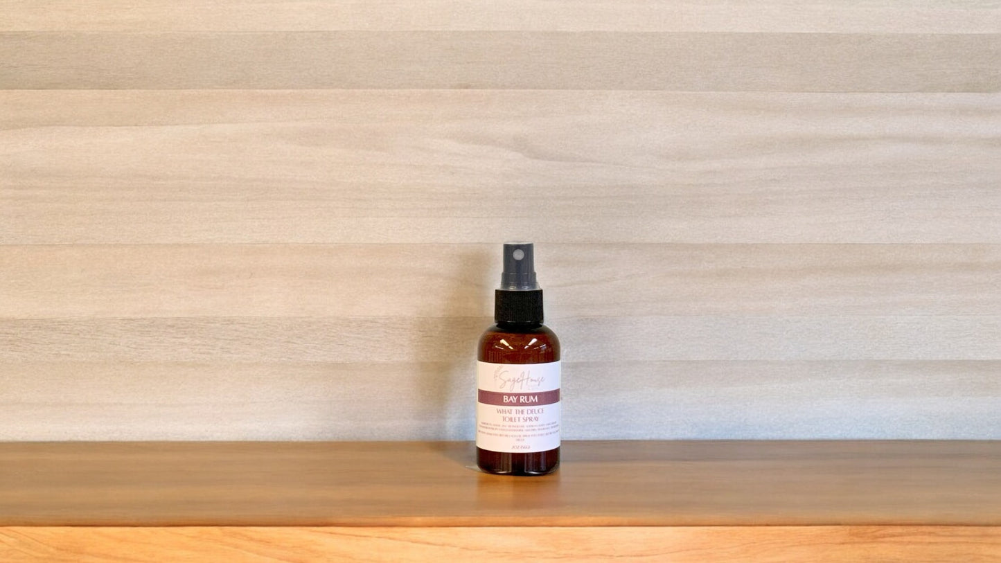 Amber colored spritz bottle with bay rum label, on wood surface
