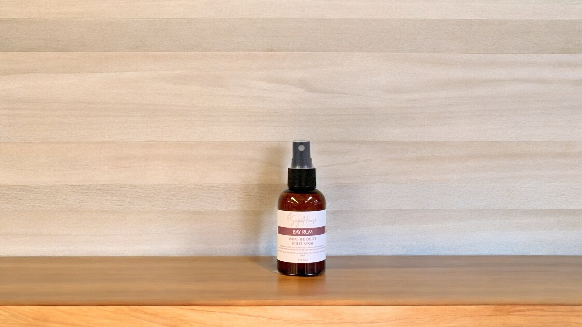 Amber colored spritz bottle with bay rum label, on wood surface
