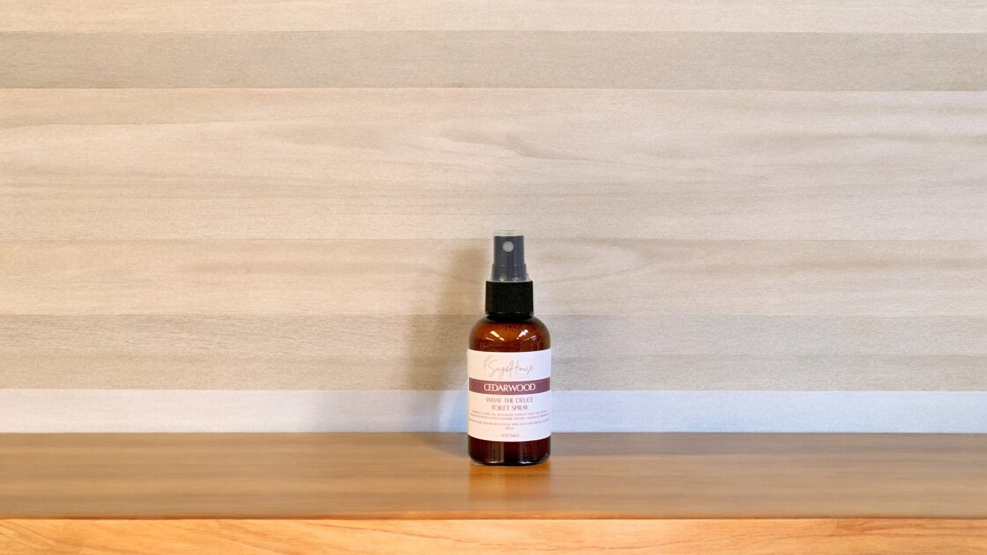 Amber colored spritz bottle with cedarwood label on wood surface