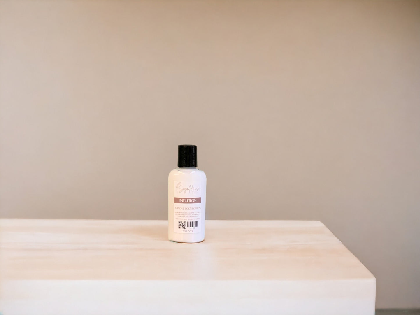 A small bottle of lotion, sitting on a light wood surface, with a tan background. 