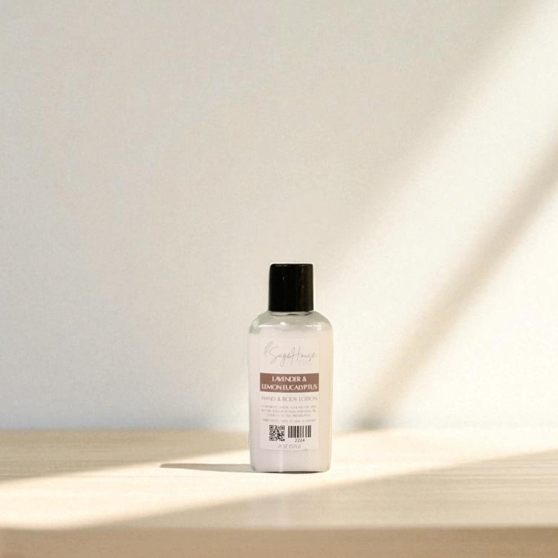 White bottle of lotion with black cap top on a light wooden surface with a blurred white background