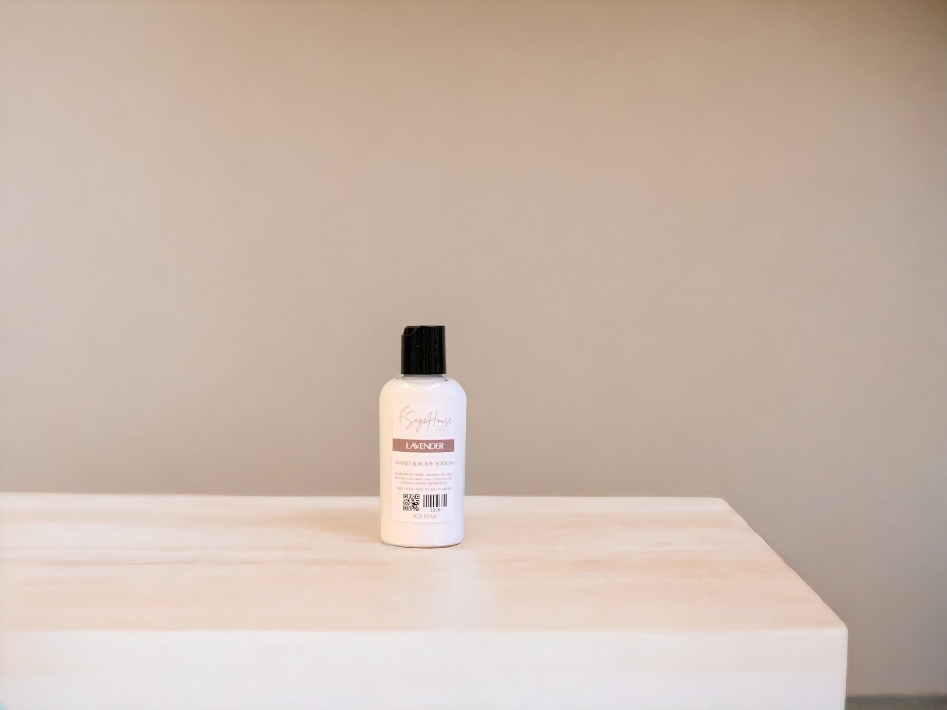A small bottle of lotion, sitting on a light wood surface, with a tan background. 