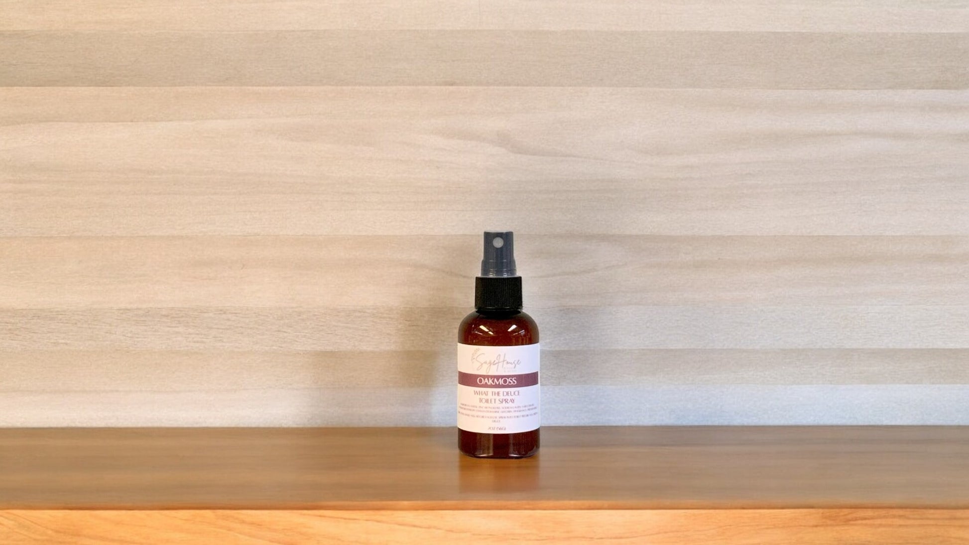 Amber colored spritz bottle with oakmoss label, on wood surface