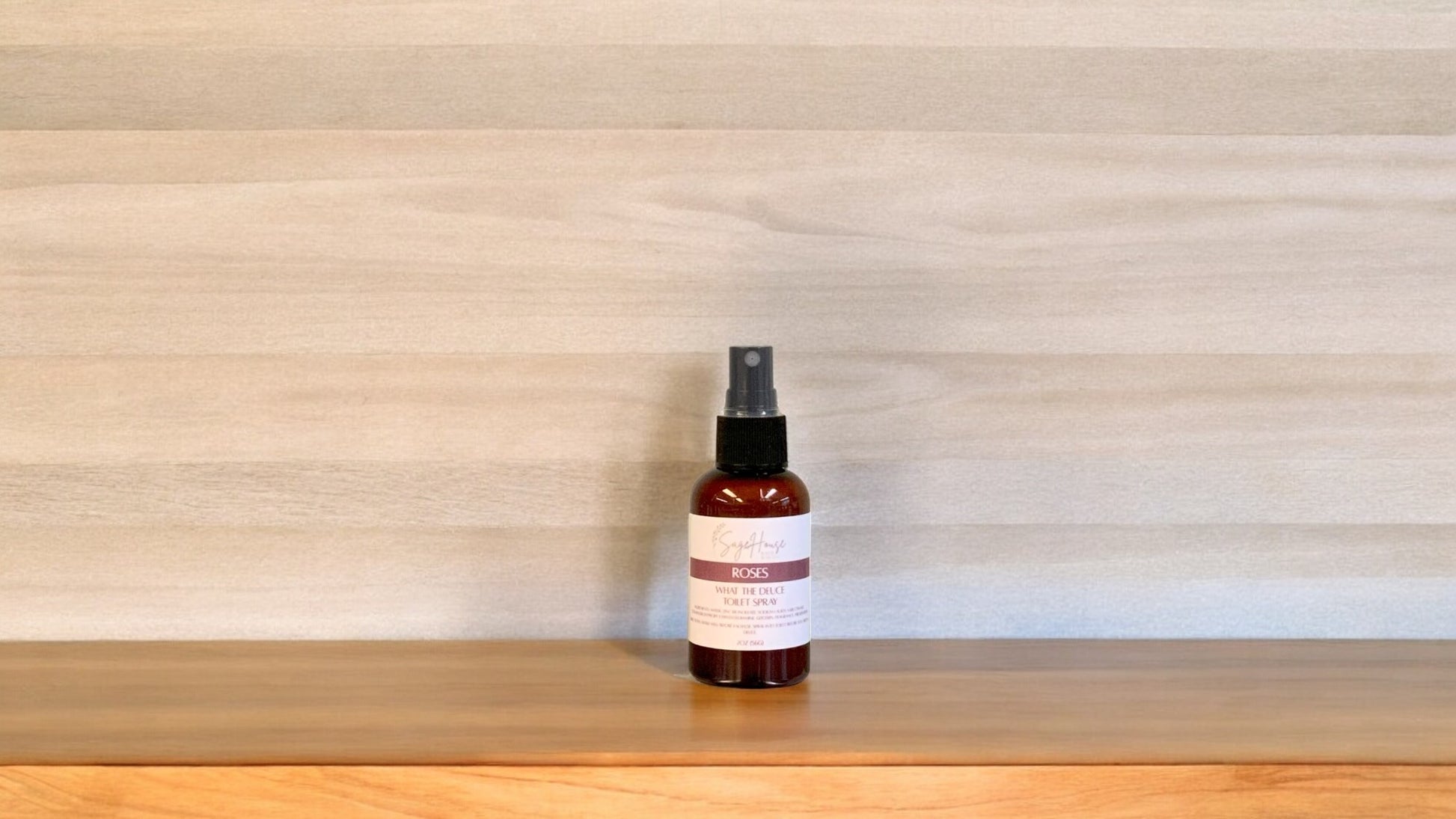 Amber colored spritz bottle with roses label, on wood surface