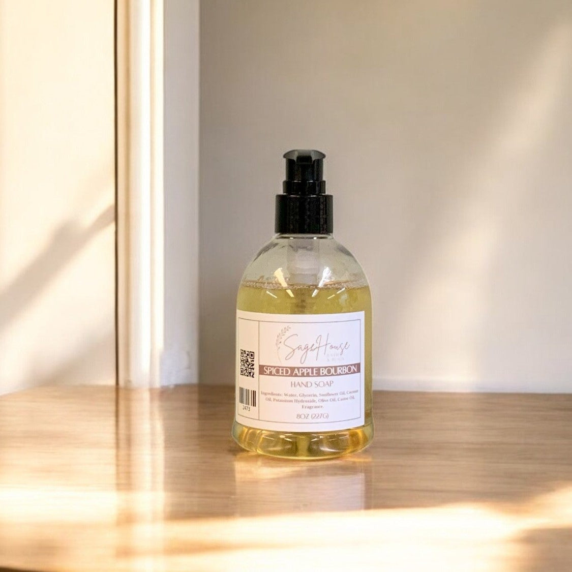 A clear plastic bottle of hand soap with a black cap, placed on a wooden surface with natural lighting.