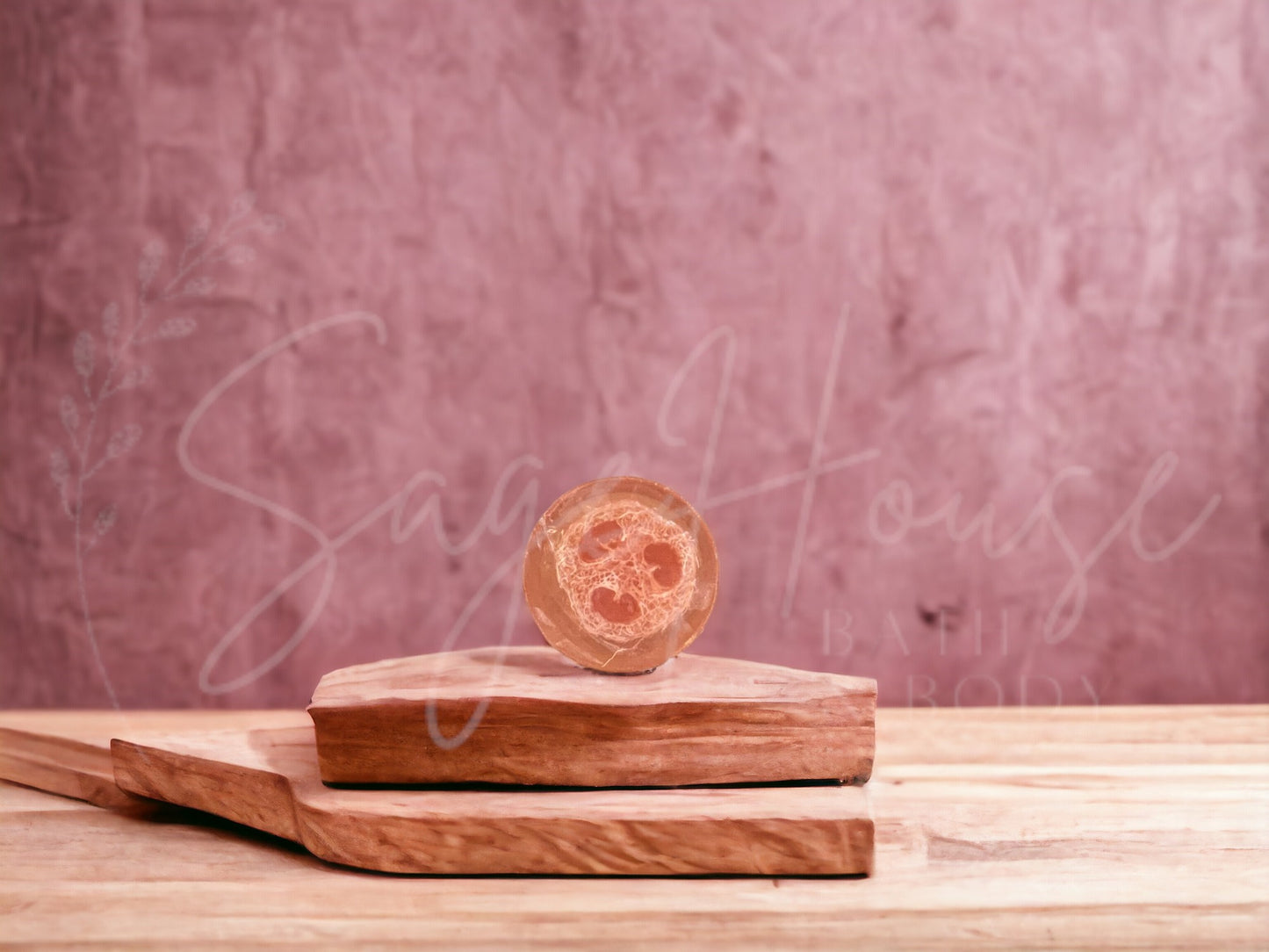 A red bar of strawberries and cream loofah soap resting on a wooden soap dish, with a pink background.