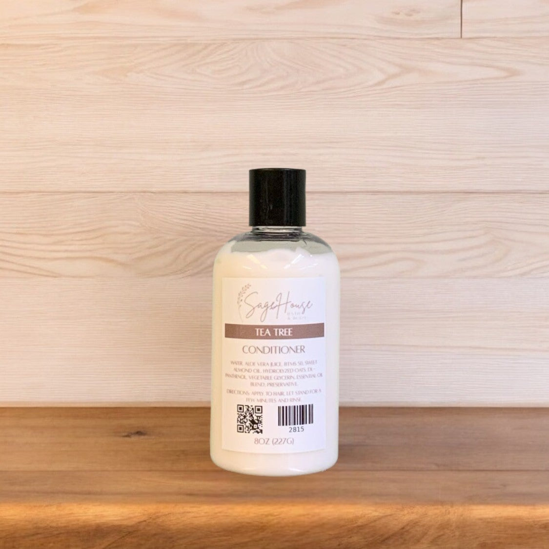 A Tea Tree conditioner in a clear bottle on a wooden surface.