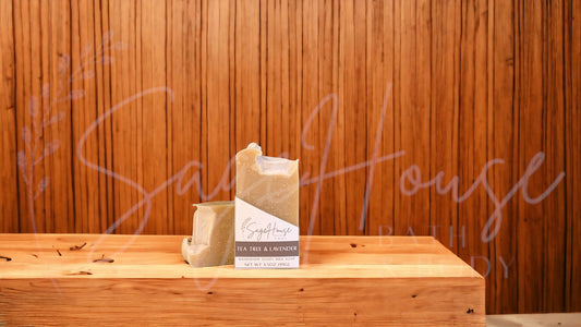A tan bar of soap in a white labeled box, on a wood surface.