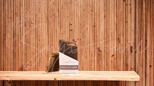A dark brown colored bar of soap with a white label. on a wood surface.