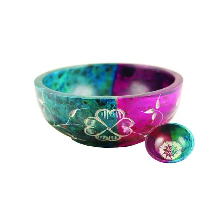 A Soapstone Bowl with Turquoise and Purple colors, and flower and sun designs on a white background