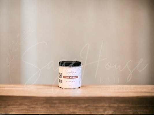 A jar of Unscented Body Butter placed on a wooden surface with a neutral background.