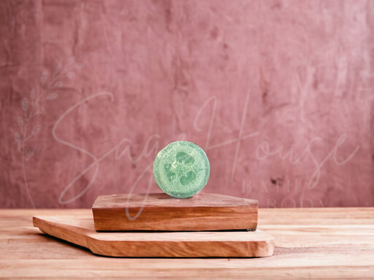 A bar of unscented loofah soap resting on a wooden soap dish, with a pink background.
