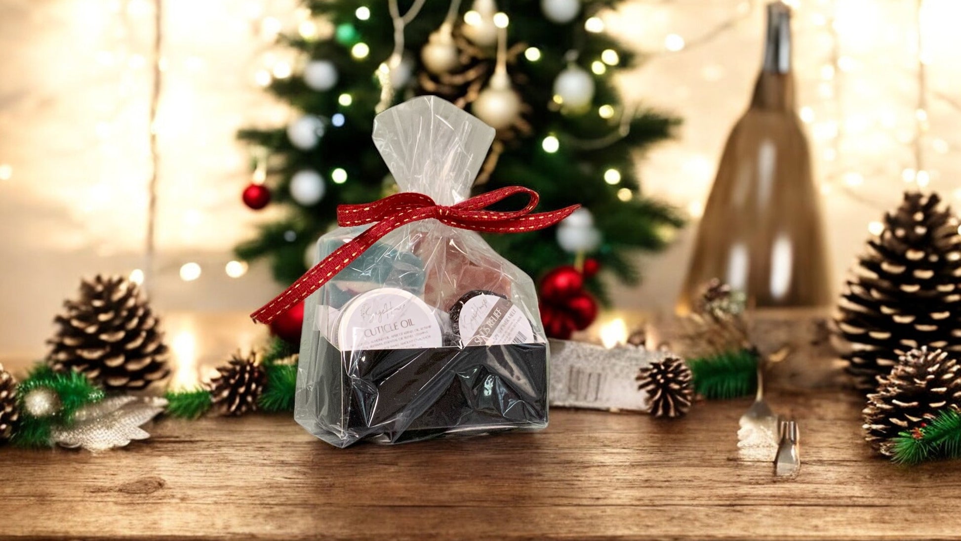A gift bag with a red ribbon and Christmas-themed decorations around it, containing various bath and body products, placed on a wooden surface with a blurred Christmas tree and lights in the background.