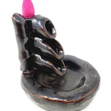 Cone incense burner that looks like stacked pipes. Incense cone placed on top.