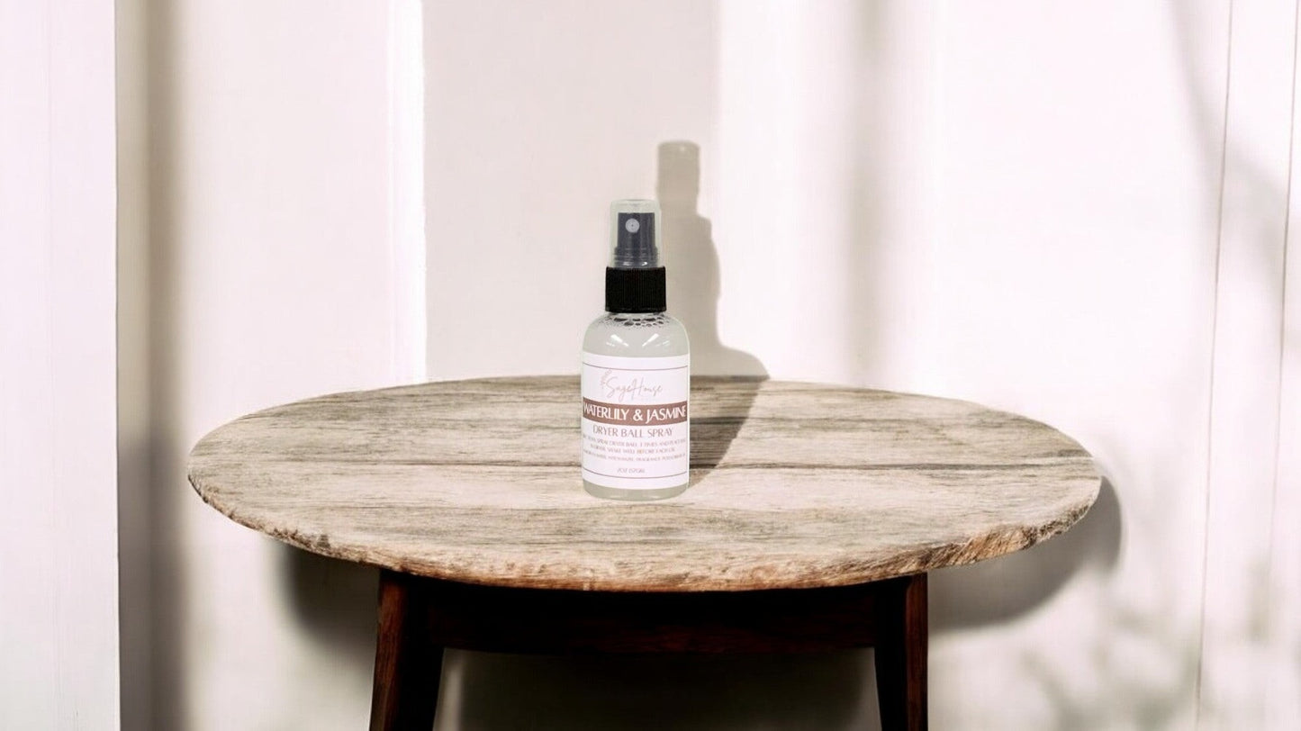 A clear bottle with black spritz top. sitting on a stone table with a white wall in the background