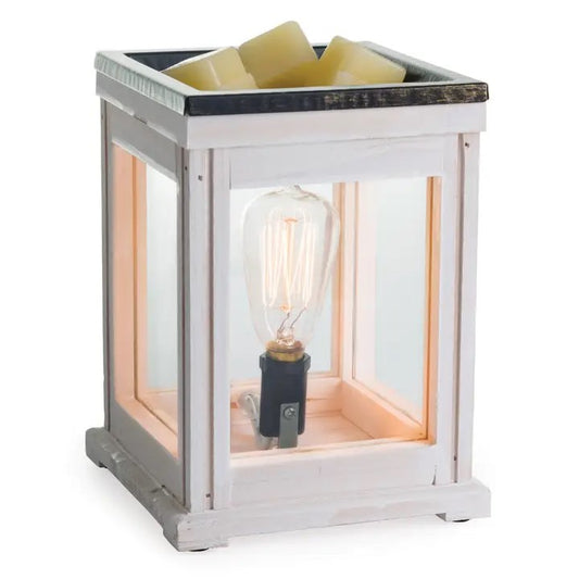 A weathered wood warmer with a clear glass enclosure and a halogen bulb, heating a dish with wax melts inside, creating a warm glow.
