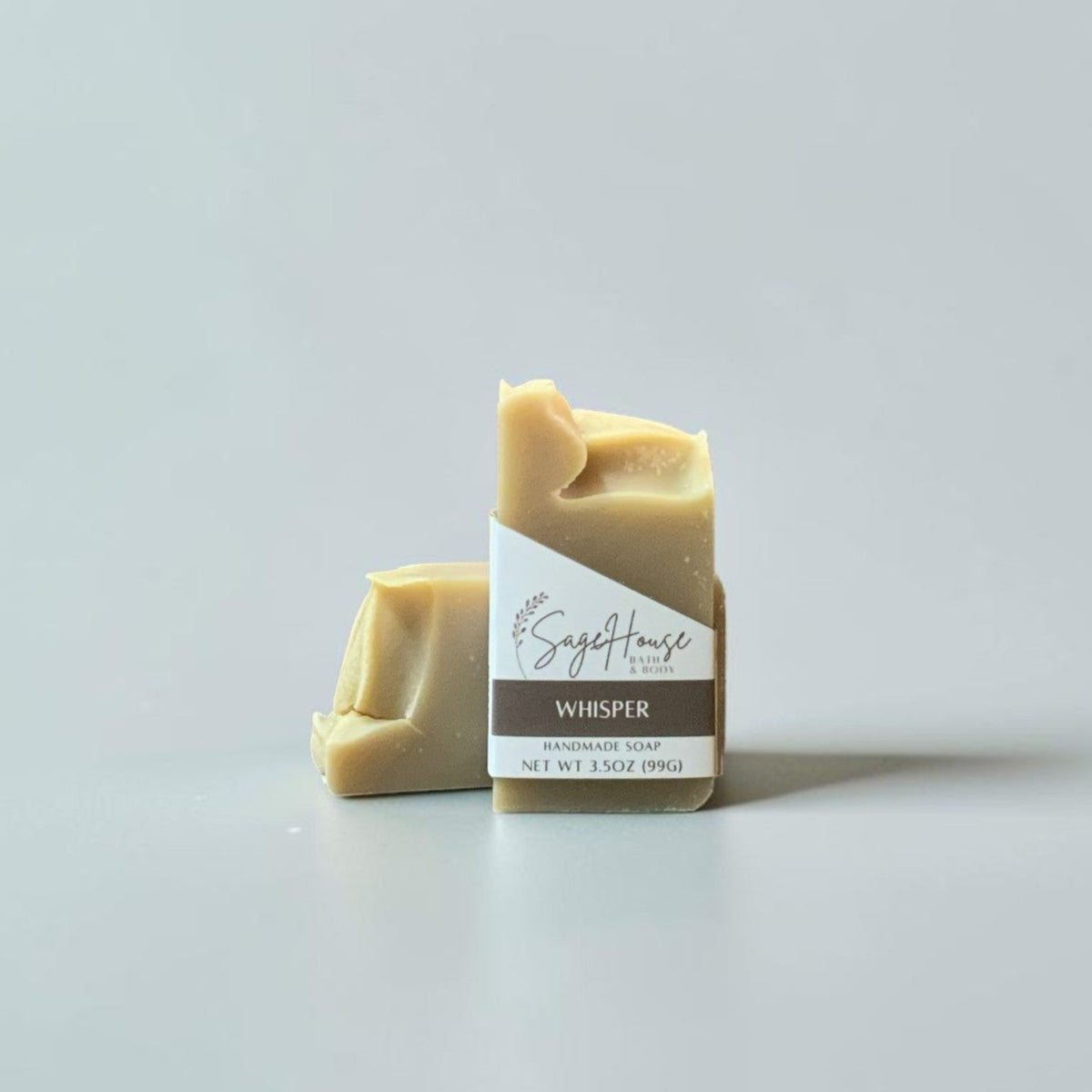 A labeled bar of soap sitting in front of a matching bar of soap. On a white background.