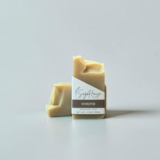 A labeled bar of soap sitting in front of a matching bar of soap. On a white background.
