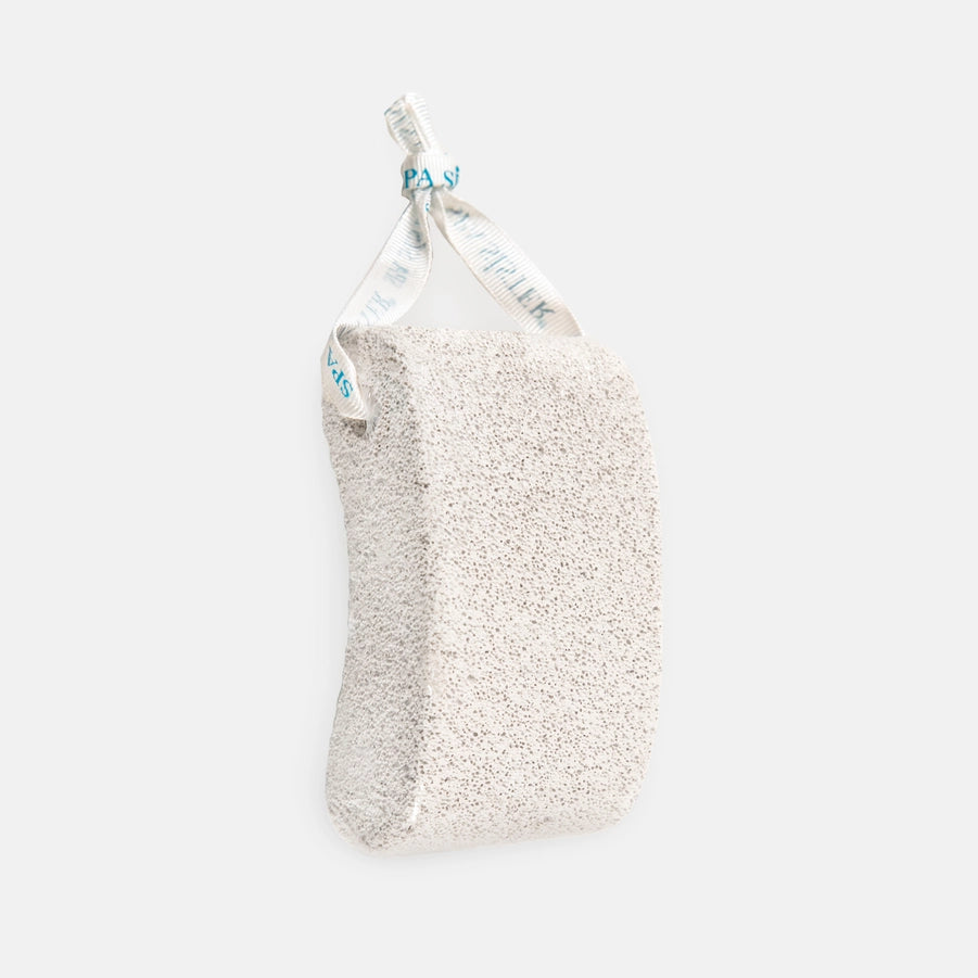 A white pumice stone with a rope attached for use.