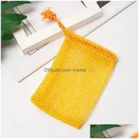 A Soap Scrub Pouch in yellow, placed on a white surface. A basket and plant in the background.