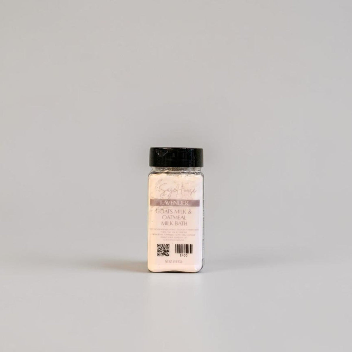 A bottle of Goat milk bath with a black cap and label. On a light gray background.